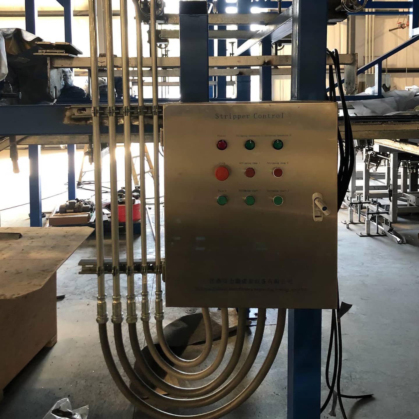 Industrial control panel connected to production equipment and electrical conduit.